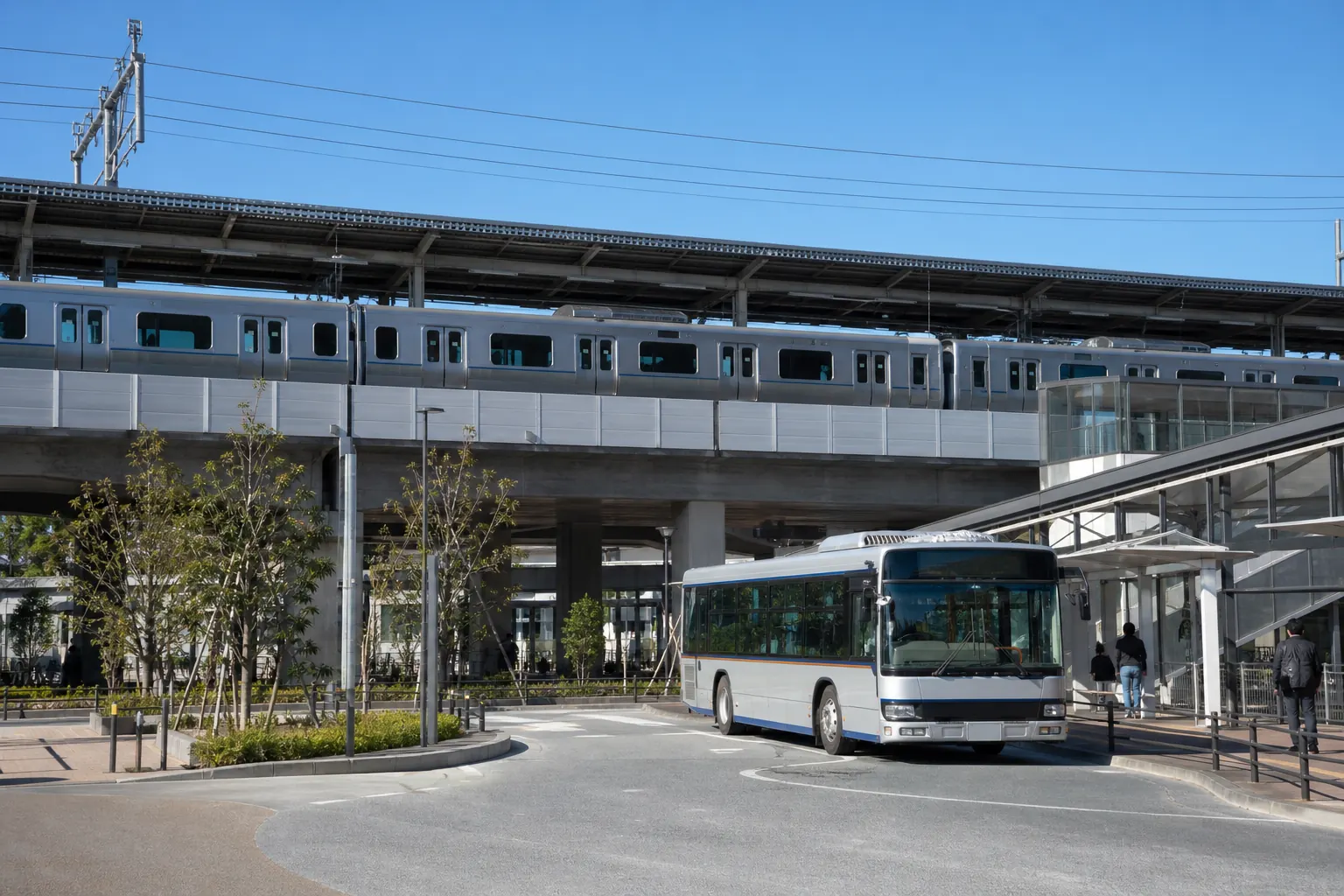 駅のホームに入ってくる通勤電車と、駅前に停まる路線バスを同じ画面に収めた写真